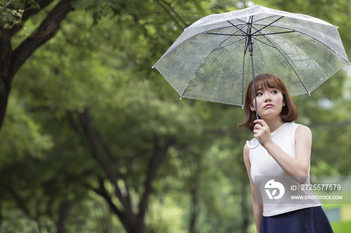 闷闷不乐的年轻女子打着雨伞