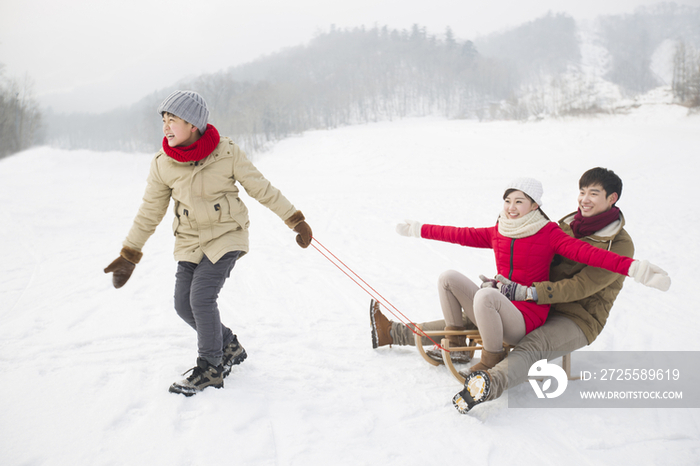 快乐的一家人在雪地上玩雪橇