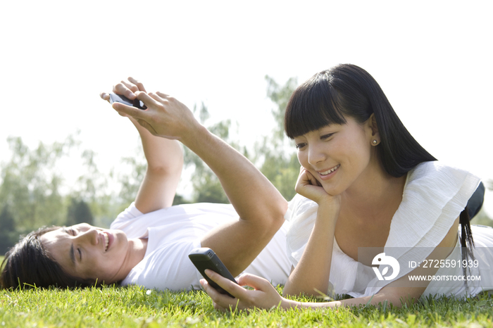 在草地上玩手机的情侣