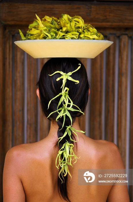 Woman holding with pot of ylang ylang on head