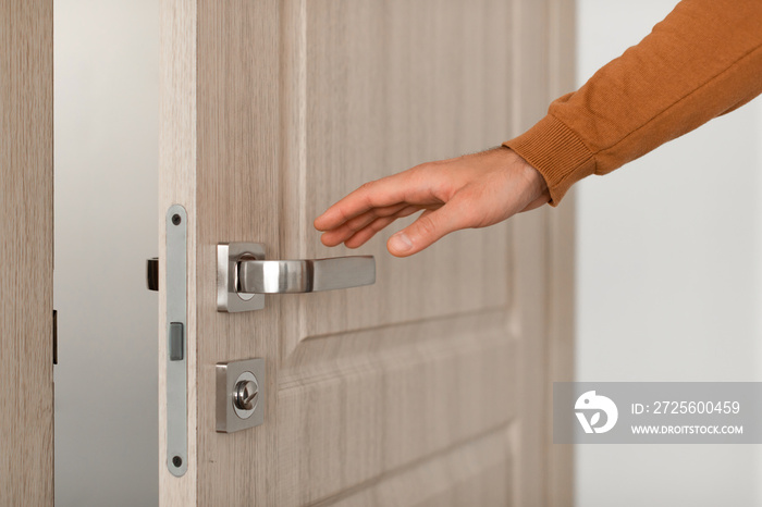 Closeup of guy opening wooden door, reaching hand to handle