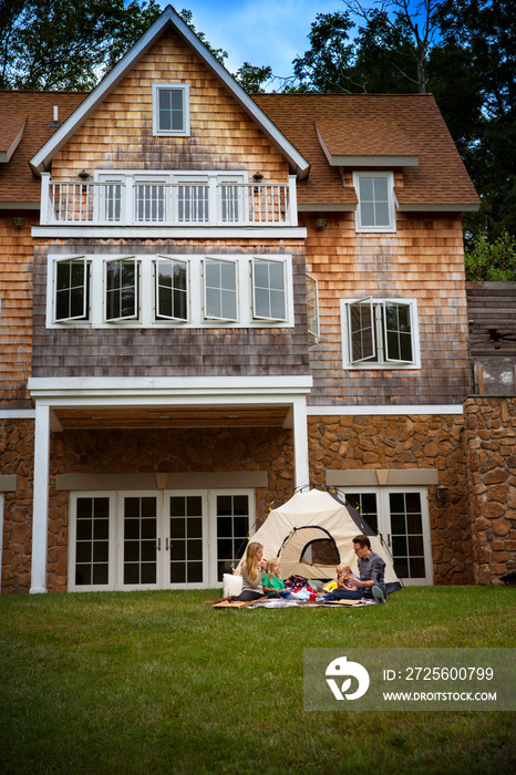 Family with two kids (6-7) playing with tent in back yard