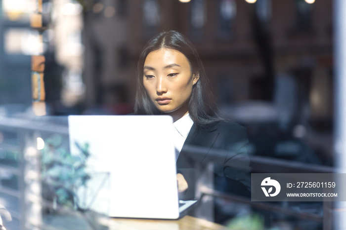 Beautiful female student working at computers, Asian woman in cafe look through word window