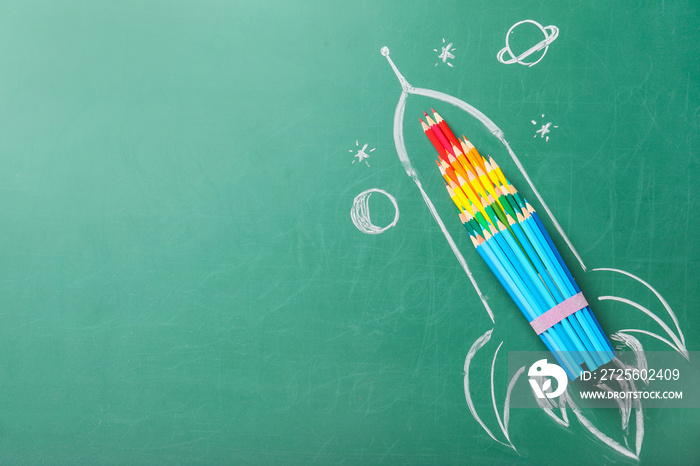 Creative composition with drawn space rocket and stationery on chalkboard