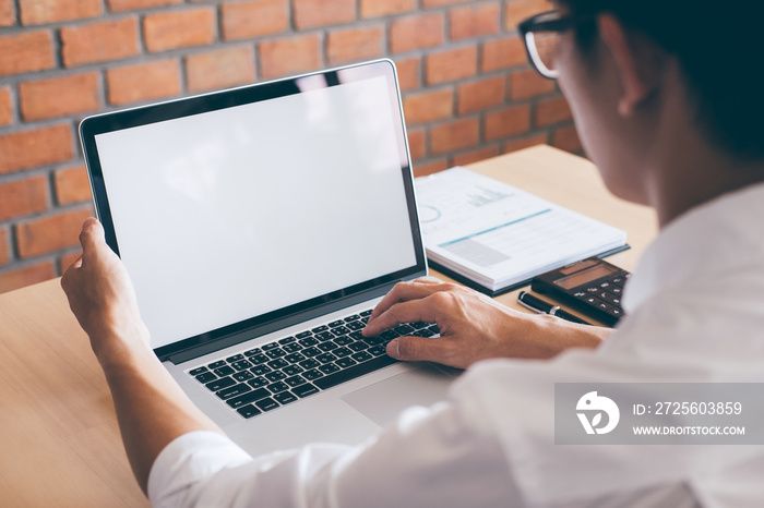 Image of Young man working in front of the laptop looking at screen with a clean white screen and bl