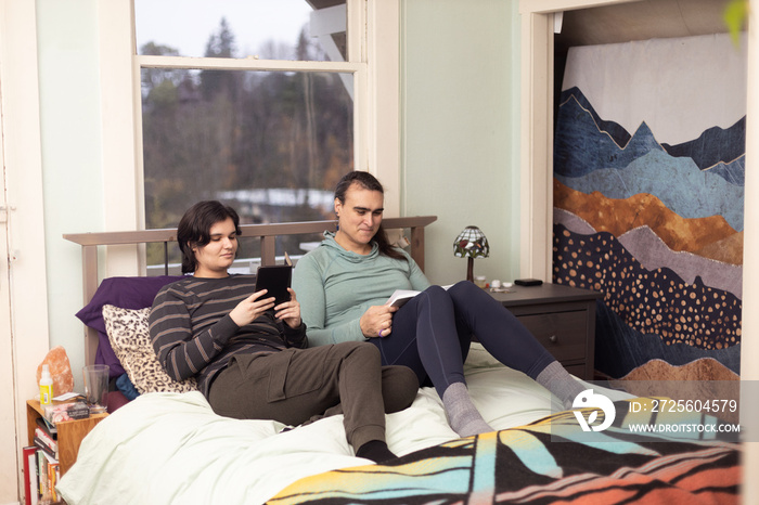 Trans friends reading on the bed.