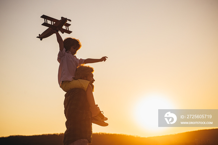 Sunset silhouette of Happy father and child son with airplane dreams of traveling. Father carrying h