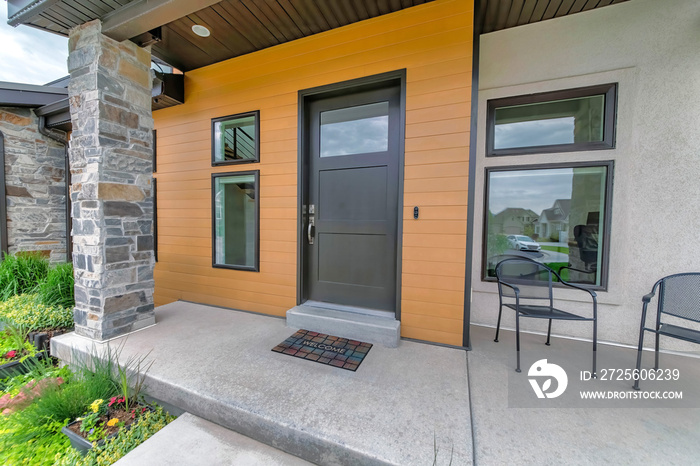 Entrance of a house with black front door and two arm chairs