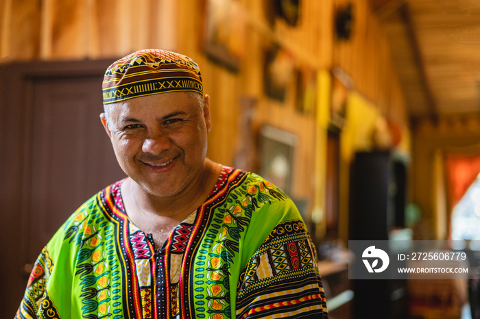 Imagen horizontal de un hombre adulto latino muy sonriente mirando a cámara en el interior de su cas