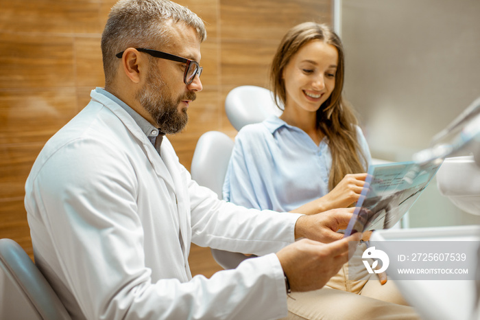 Young patient with senior dentist during a medical consultation at the dental office, doctor showing