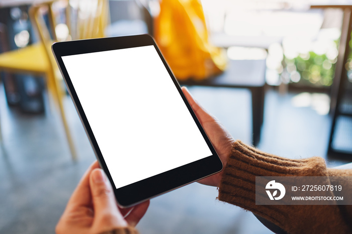 Mockup image of a woman sitting and holding black tablet pc with blank white desktop screen