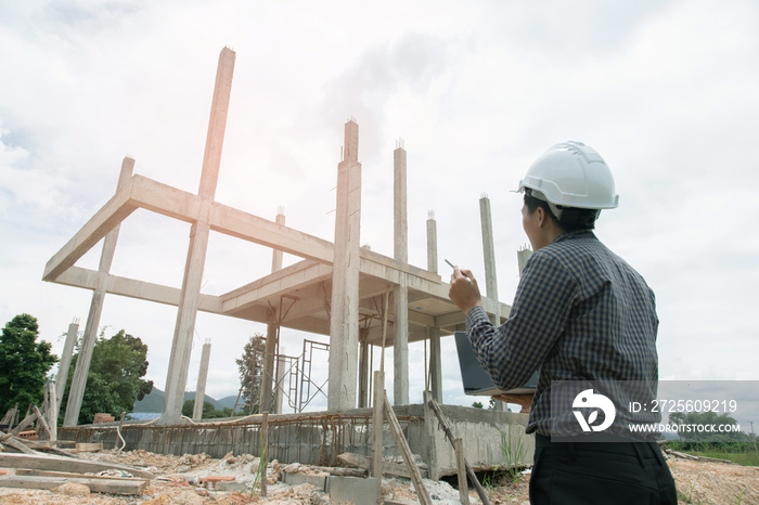 Asian manager of engineer architects in white helmet safety on construction site stands to look buil