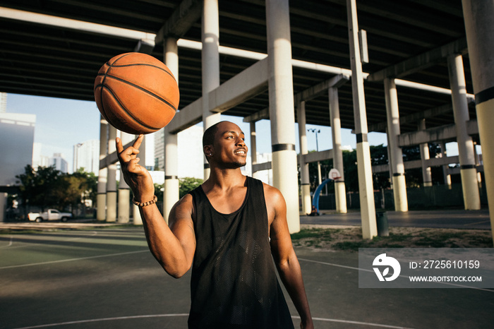 Man on basketball court balancing basketball on finger looking away