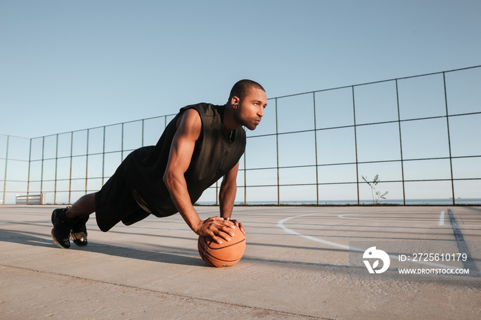 Sports man doing plank exercise with ball at the playground