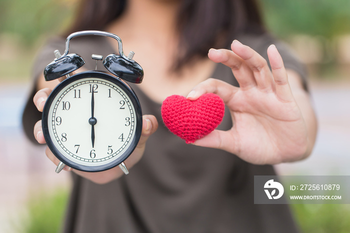 give time with love, showing retro clock and red heart on hand.