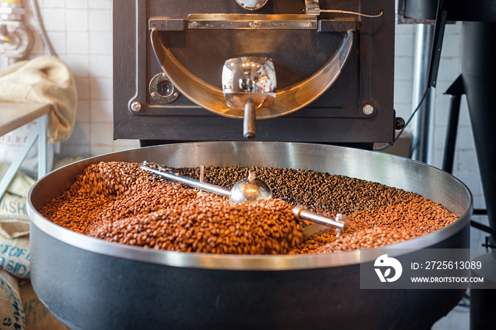 Freshly roasted coffee beans from a large roaster in the cooling cylinder. Motion blur on the beans,