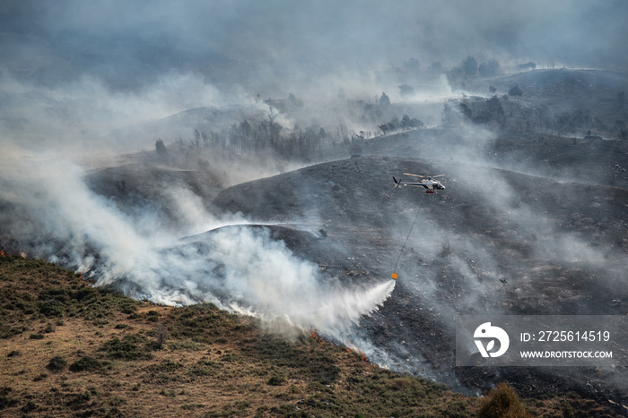 消防直升机在森林火灾或野火中用水桶滴水。