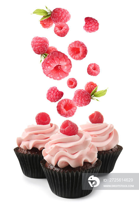 Delicious cupcakes and falling raspberry on white background