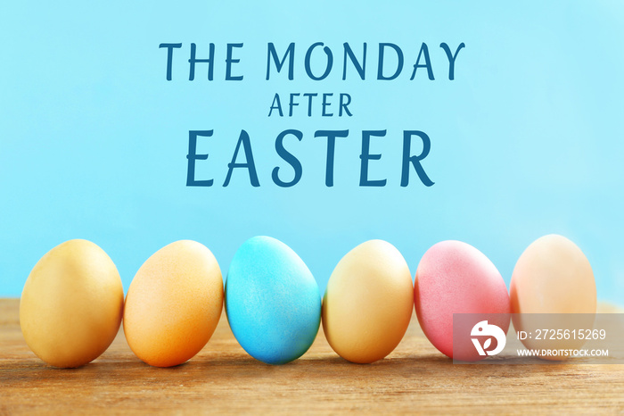 Colorful Easter eggs on wooden table against blue background