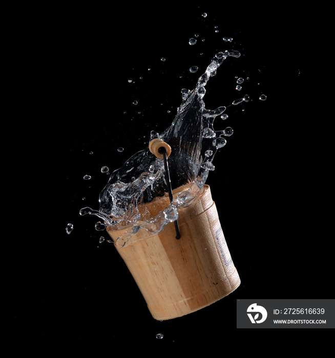 Wooden bucket with water splash or explosion flying in the air isolated on black background,Motion b