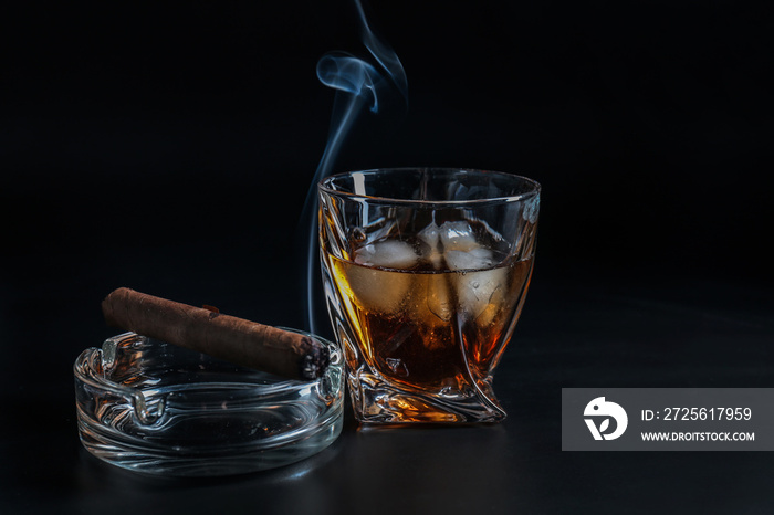 Glass of cold whiskey with cigar on dark background