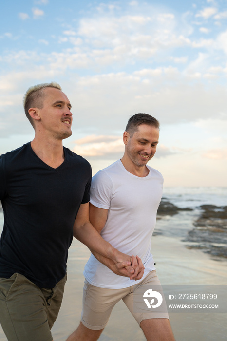 一对同性恋情侣在海滩上携手奔跑，面带微笑