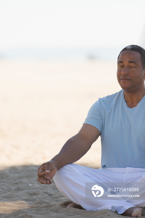 Serene senior man meditating on beach