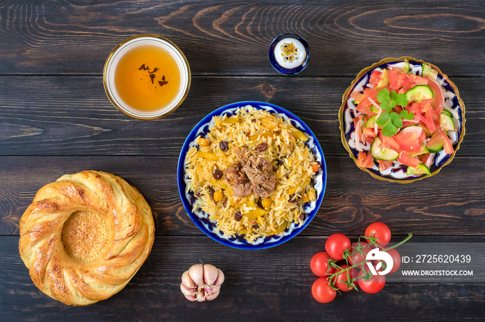 National Uzbek pilaf with meat, achichuk salad of tomato, cucumber, onion in plate with traditional 