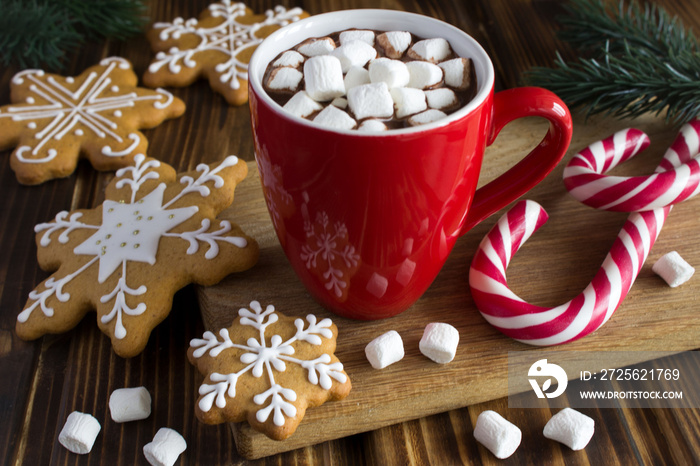 红杯子里有棉花糖的热巧克力，木制砧板上有圣诞饼干