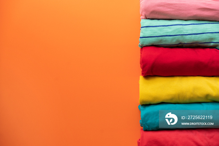 close up of rolled colorful clothes on orange background