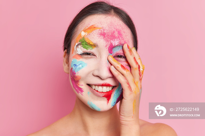 面部艺术概念。积极的少数民族年轻女子脸上涂满了五颜六色的颜料，笑容满面