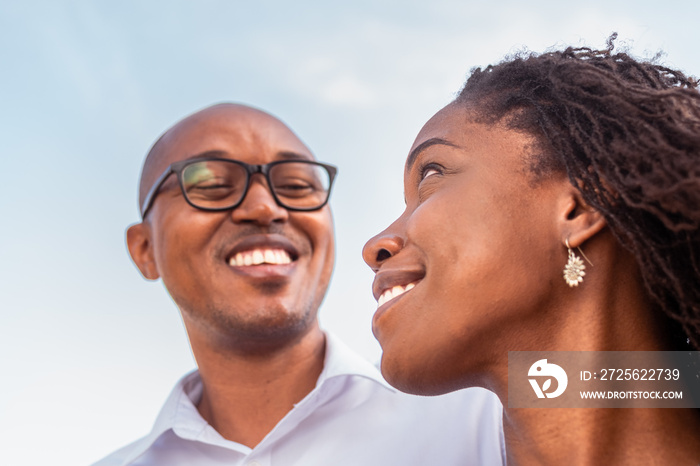 Attractive black woman smiling, looking over her shoulder at her partner. Loving African couple star