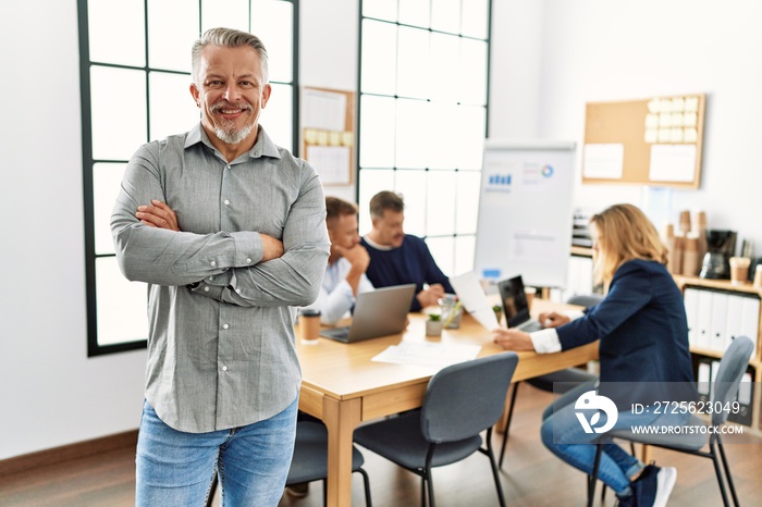 Middle age caucasian businessman smiling happy standing with arms crossed gesture at the office duri