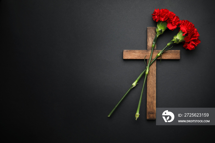 Carnation flowers with wooden cross on dark background