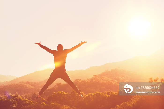 Happy man jumping at top of mountain with sunset sky abstract background.