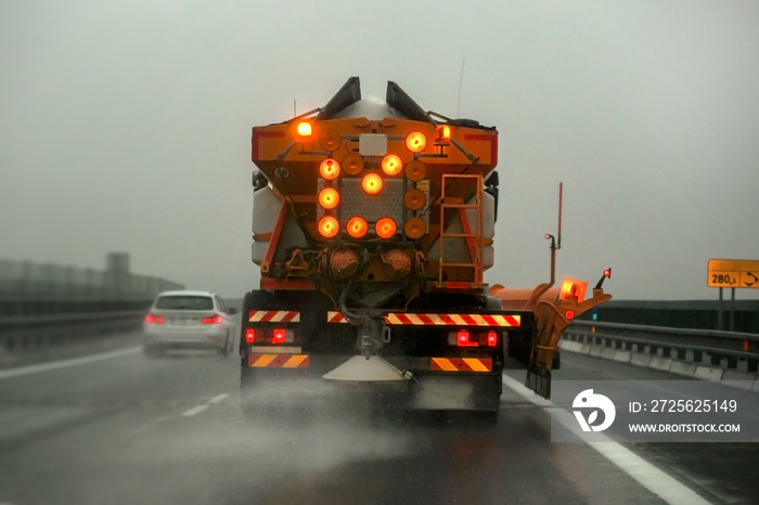 公路养护砂砾车在结冰的沥青路面上撒除冰盐