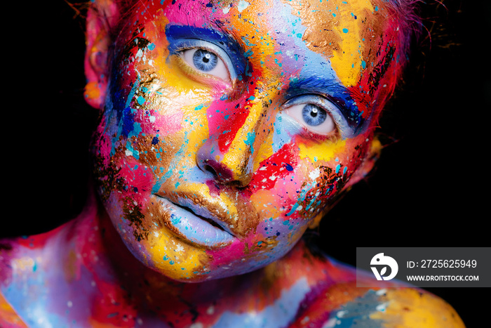 一个女人的肖像，脸上画着五颜六色的画笔。明亮的蓝眼睛。广告空间