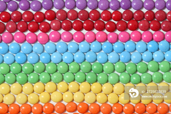 Colorful and sweet smarties background. Chocolate buttons in lines and colors of rainbow.
