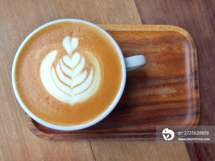 flat white coffee with latte art, this pattern is commonly called  tulip  on wooden saucer and table
