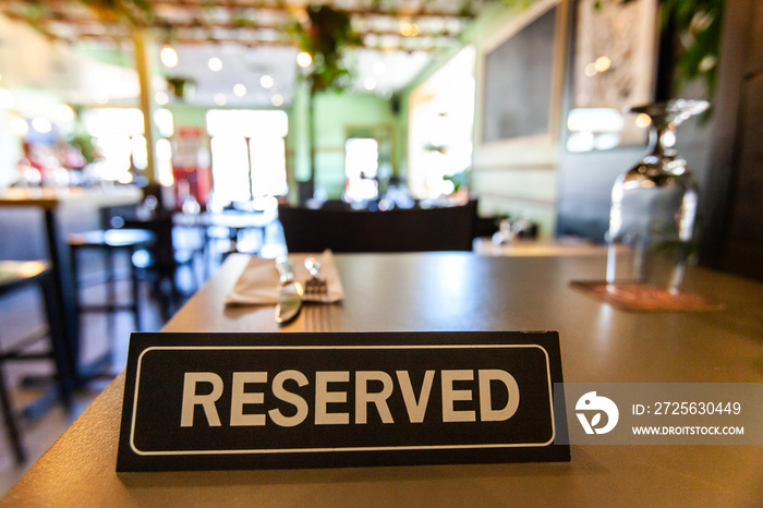 Reserved sign on restaurant table. A table reservation sign is viewed close up inside a trendy bistr