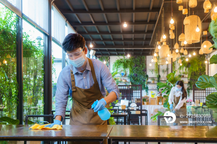 Portrait attractive Asian restaurant employee wear face mask and face shield cleaning table and floo