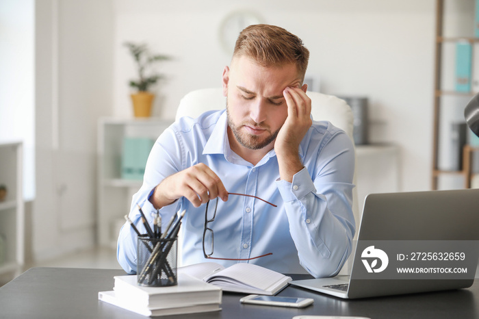 Young man suffering from headache in office