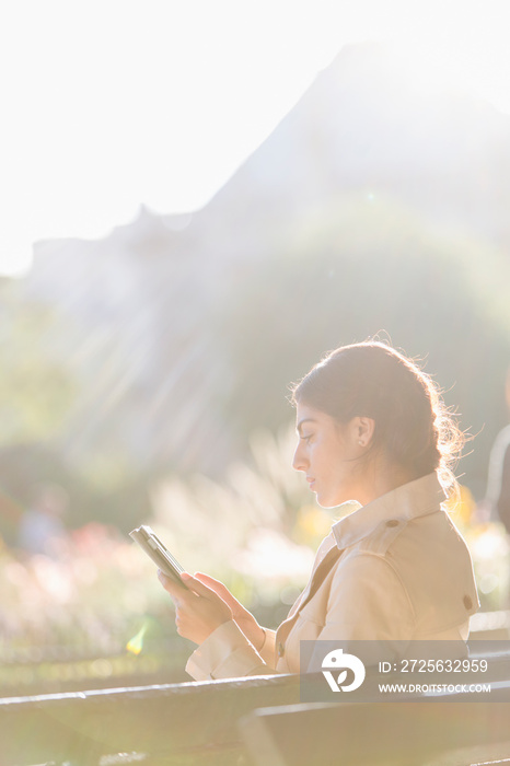 Businesswoman using digital tablet on sunny bench