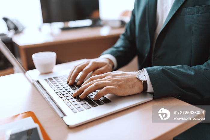 Close up of Caucasian businessman typing on keyboard. Office interior.