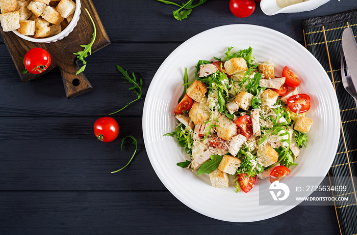 Healthy grilled chicken Caesar salad with tomatoes, cheese and croutons. North American cuisine. Top