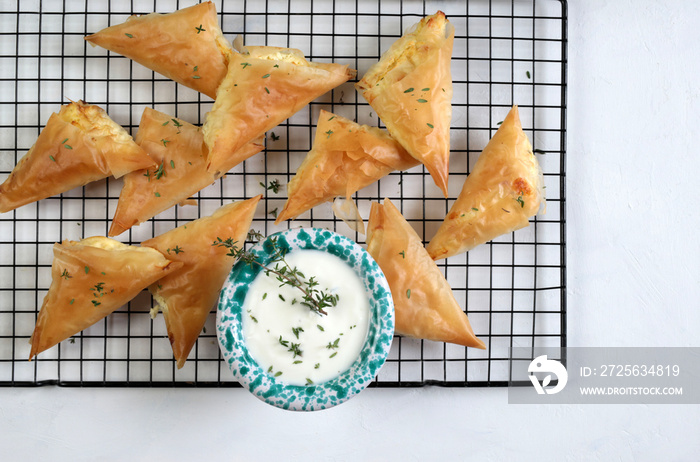 Cucina greca. Tiropita, triangoli con formaggio feta greco su sfondo bianco. Vista dallalto.