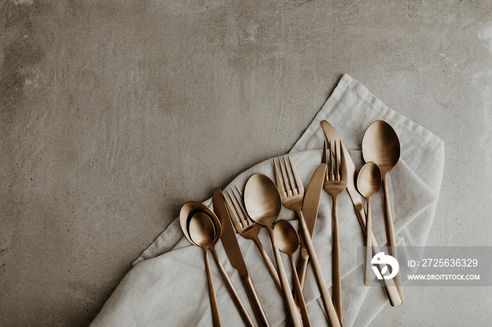 Golden cutlery composition on grey background