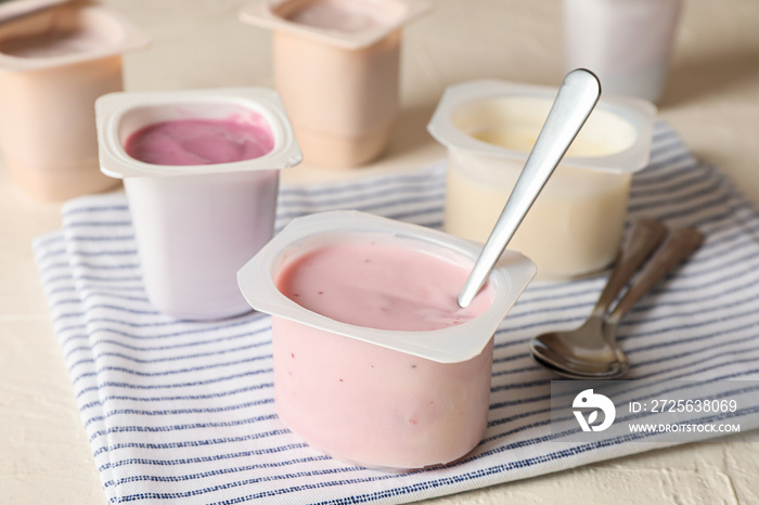 Composition with plastic cups with yogurt on white table