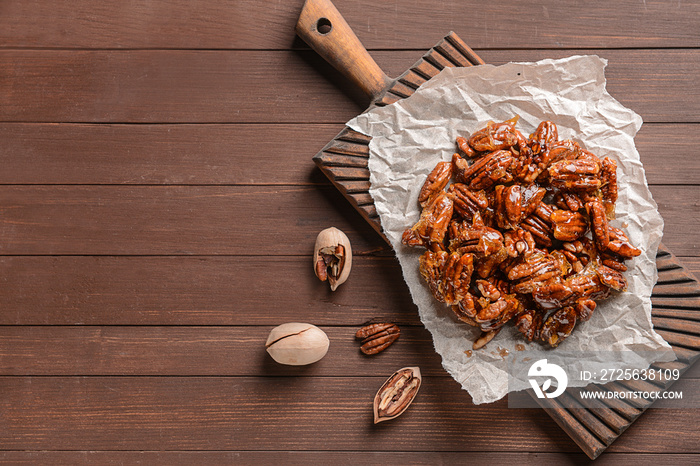 Tasty candied pecan nuts on wooden table