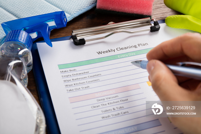 Person Hand Filling Weekly Cleaning Plan Form